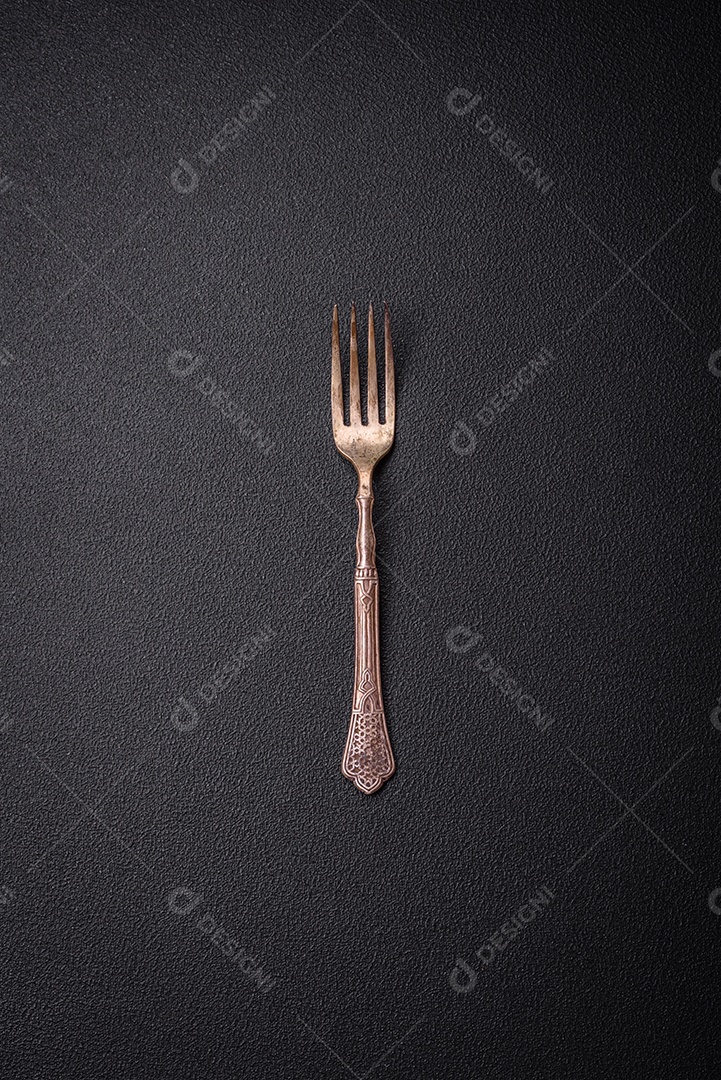 Faca e garfo de cozinha feitos de aço em um fundo escuro de concreto