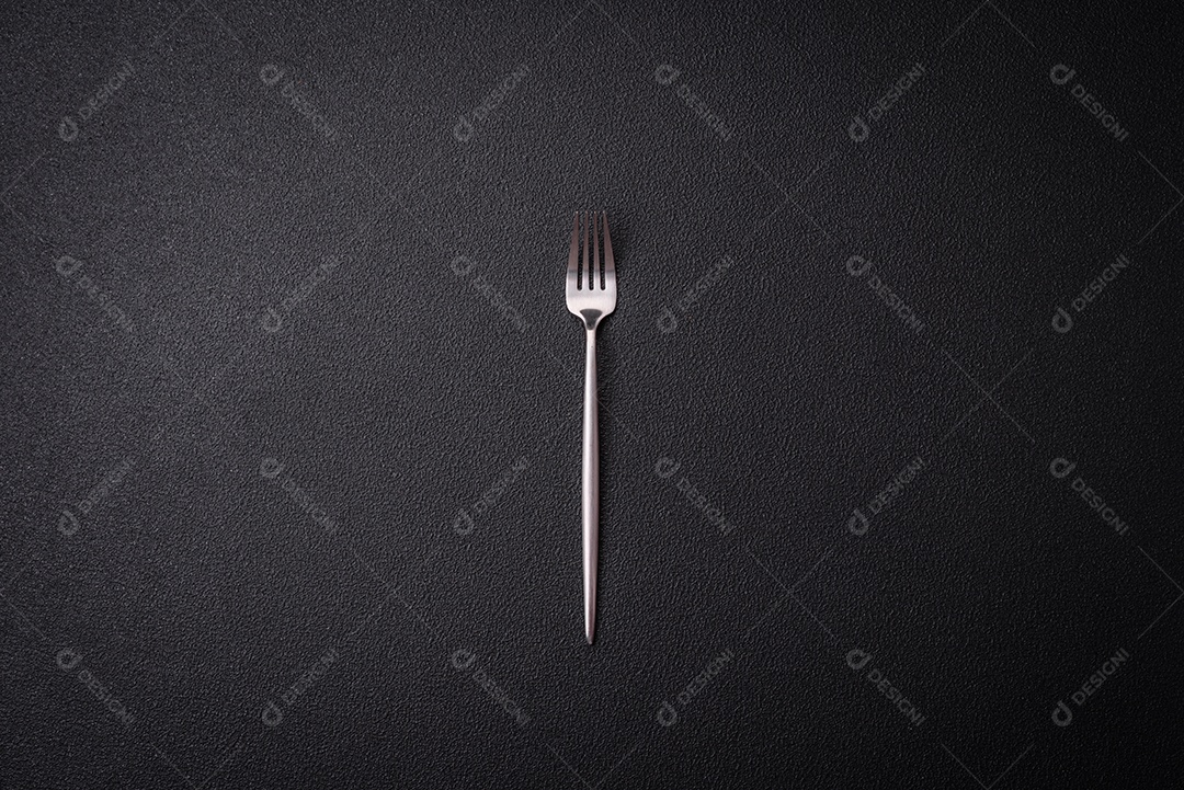 Faca e garfo de cozinha feitos de aço em um fundo escuro de concreto