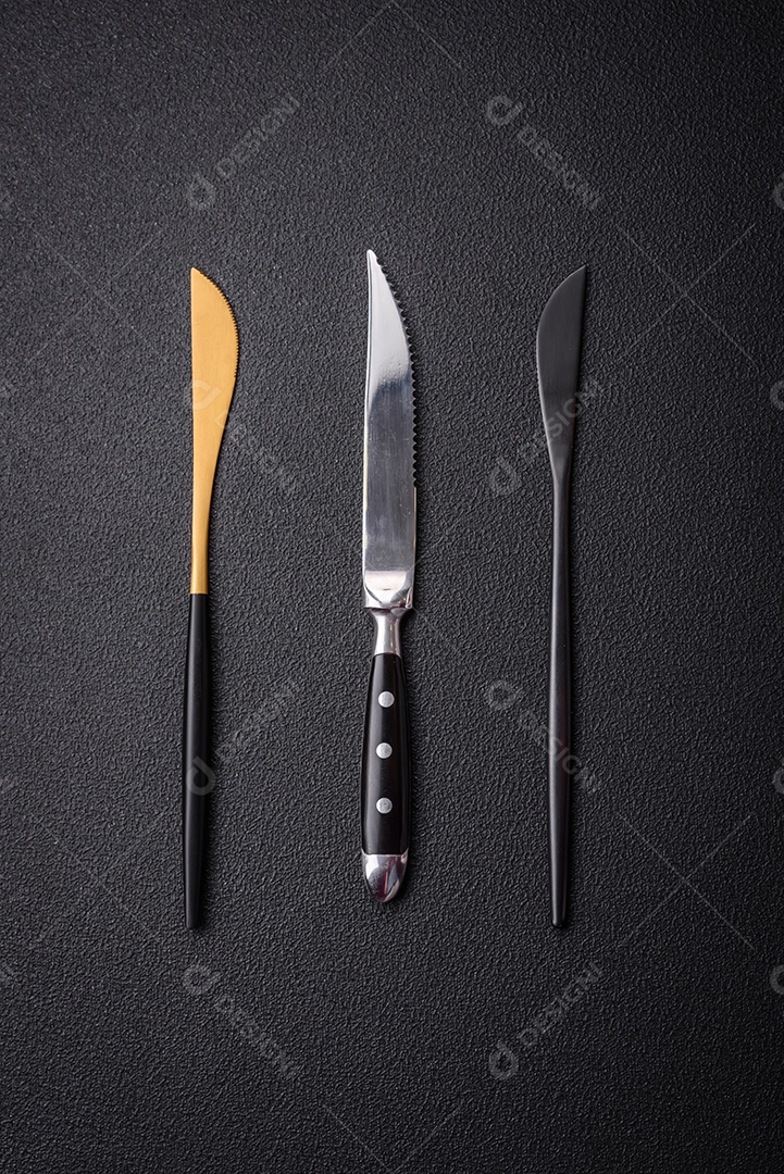 Faca e garfo de cozinha feitos de aço em um fundo escuro de concreto