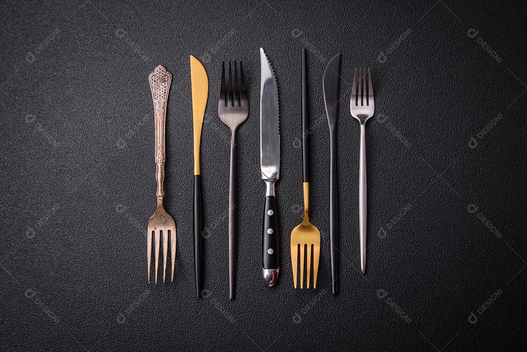 Faca e garfo de cozinha feitos de aço em um fundo escuro de concreto