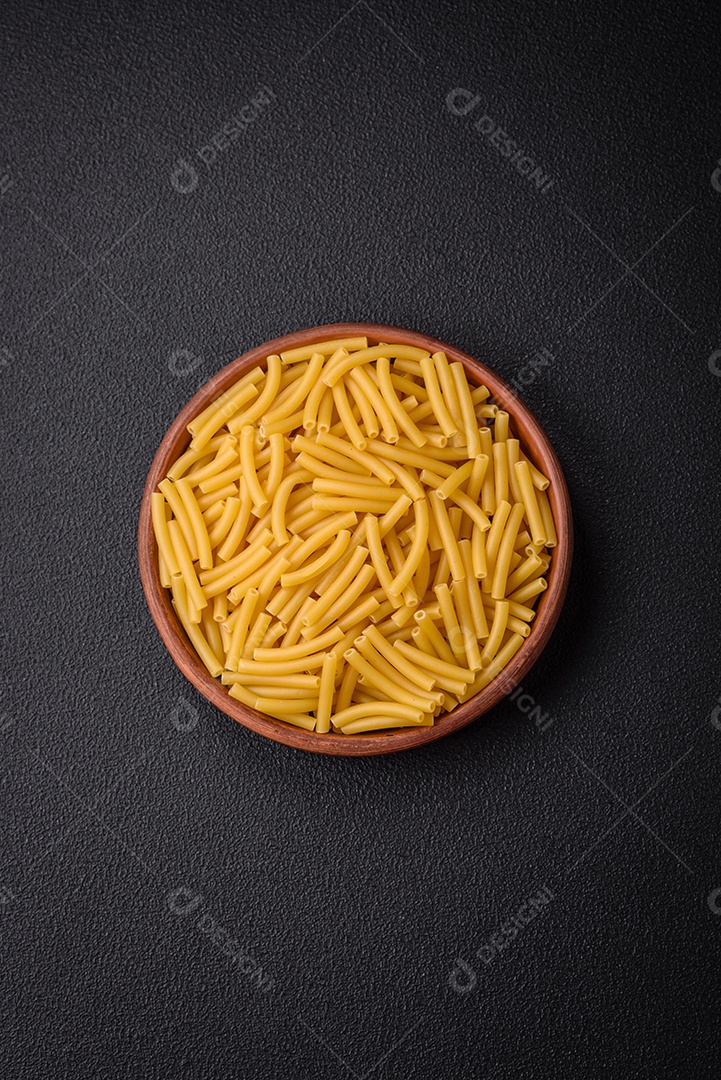 Massa de trigo integral crua com sal e especiarias em uma placa de cerâmica sobre um fundo escuro e texturizado