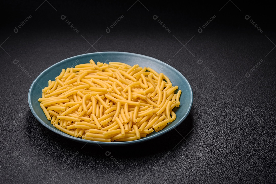 Massa de trigo integral crua com sal e especiarias em uma placa de cerâmica sobre um fundo escuro e texturizado