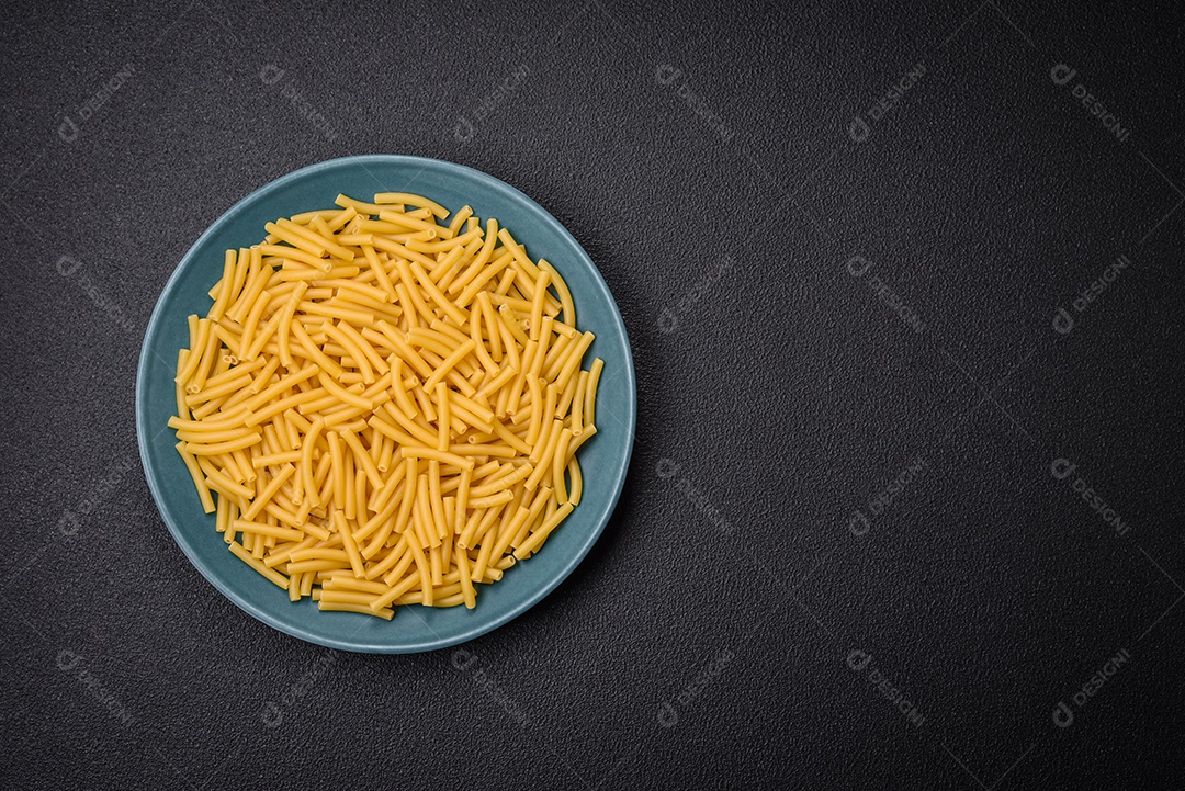 Massa de trigo integral crua com sal e especiarias em uma placa de cerâmica sobre um fundo escuro e texturizado