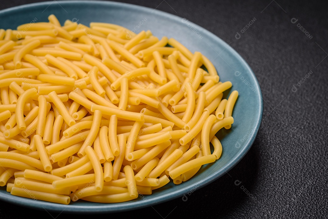 Massa de trigo integral crua com sal e especiarias em uma placa de cerâmica sobre um fundo escuro e texturizado