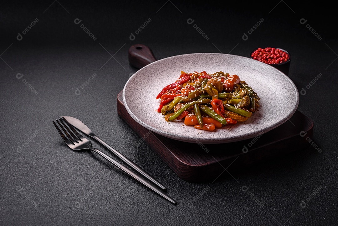 Mistura de legumes, milho, cenoura, pimentão, brócolis, cebola em molho teriyaki em uma placa de cerâmica sobre um fundo escuro de concreto