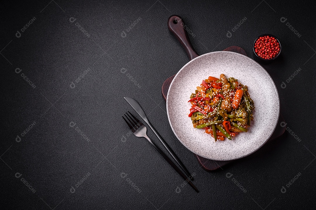 Mistura de legumes, milho, cenoura, pimentão, brócolis, cebola em molho teriyaki em uma placa de cerâmica sobre um fundo escuro de concreto