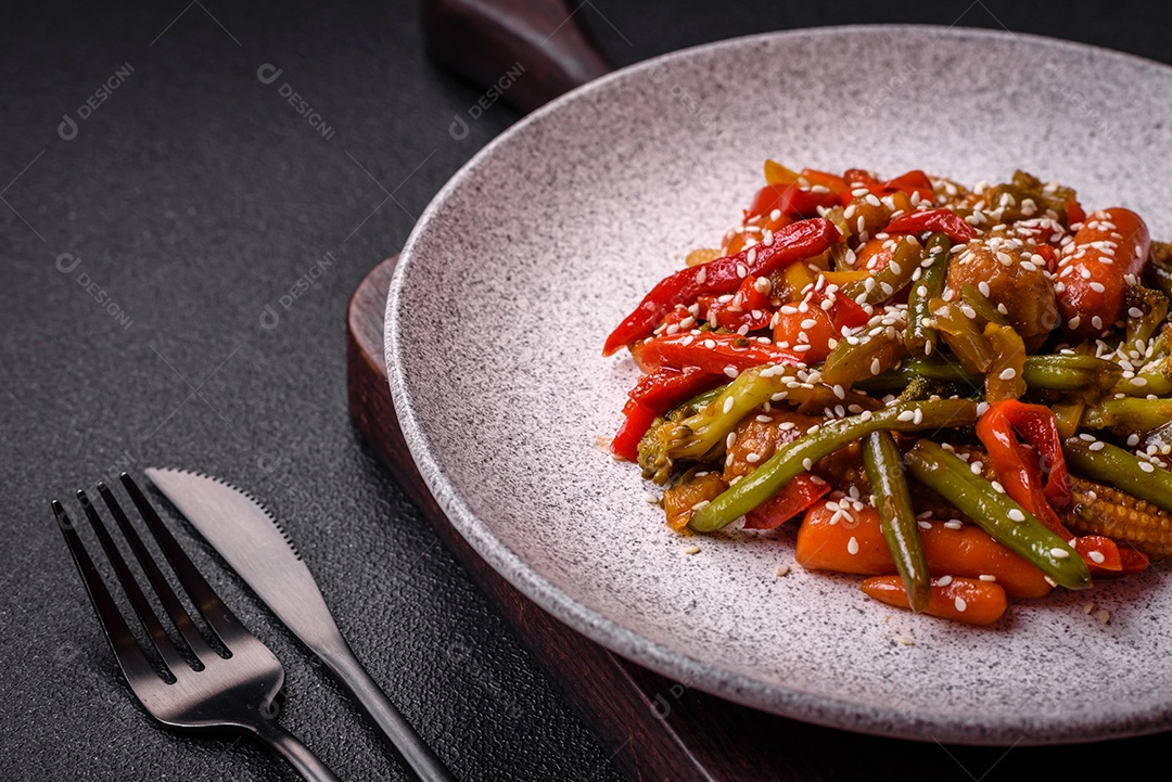 Mistura de legumes, milho, cenoura, pimentão, brócolis, cebola em molho teriyaki em uma placa de cerâmica sobre um fundo escuro de concreto