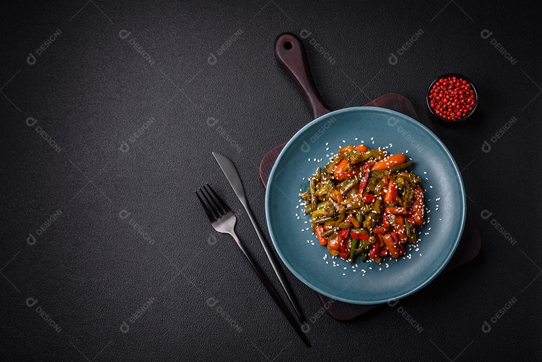 Mistura de legumes, milho, cenoura, pimentão, brócolis, cebola em molho teriyaki em uma placa de cerâmica sobre um fundo escuro de concreto