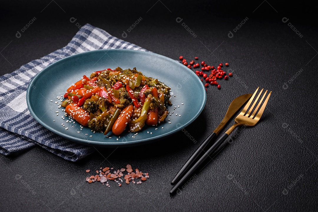 Mistura de legumes, milho, cenoura, pimentão, brócolis, cebola em molho teriyaki em uma placa de cerâmica sobre um fundo escuro de concreto