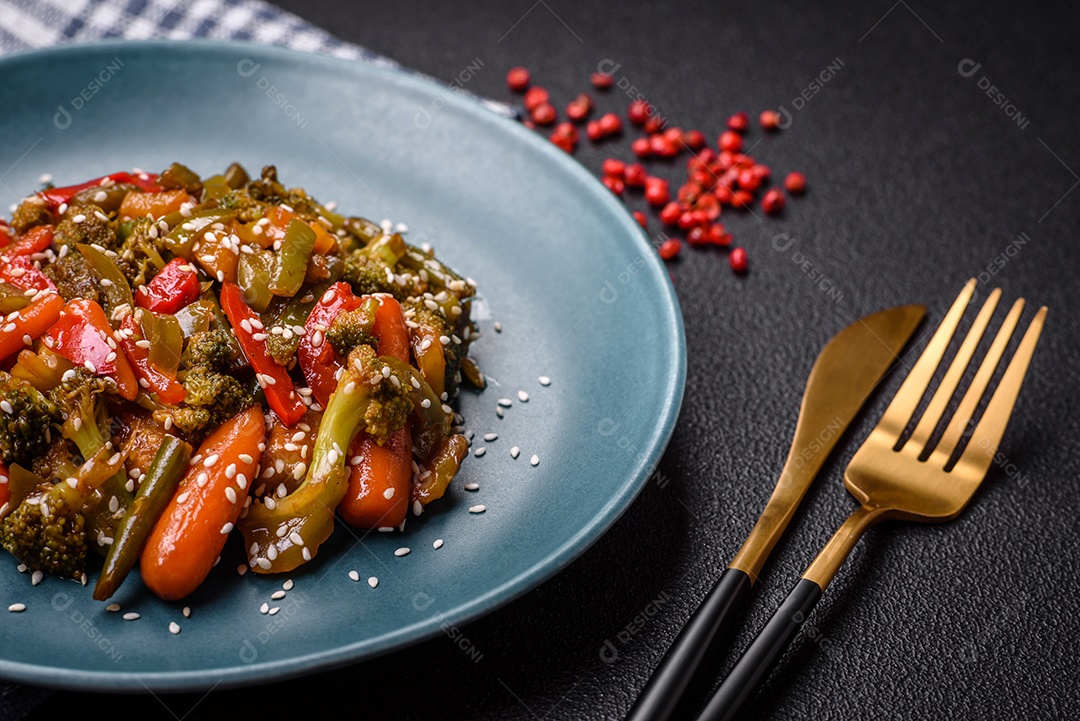 Mistura de legumes, milho, cenoura, pimentão, brócolis, cebola em molho teriyaki em uma placa de cerâmica sobre um fundo escuro de concreto