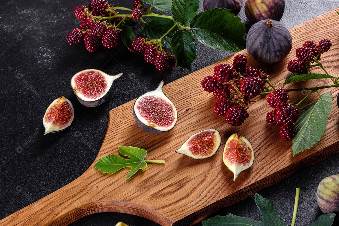 Figos frescos e suculentos e amoras em um fundo escuro.