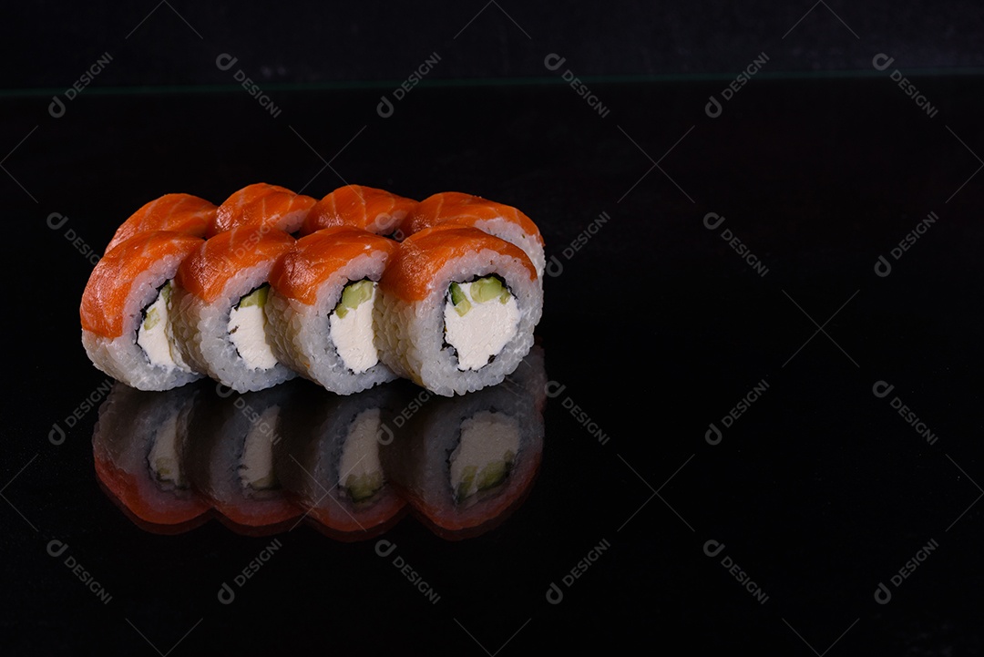 Rolos de sushi lindos e deliciosos frescos em um fundo isolado preto. Elementos da culinária japonesa