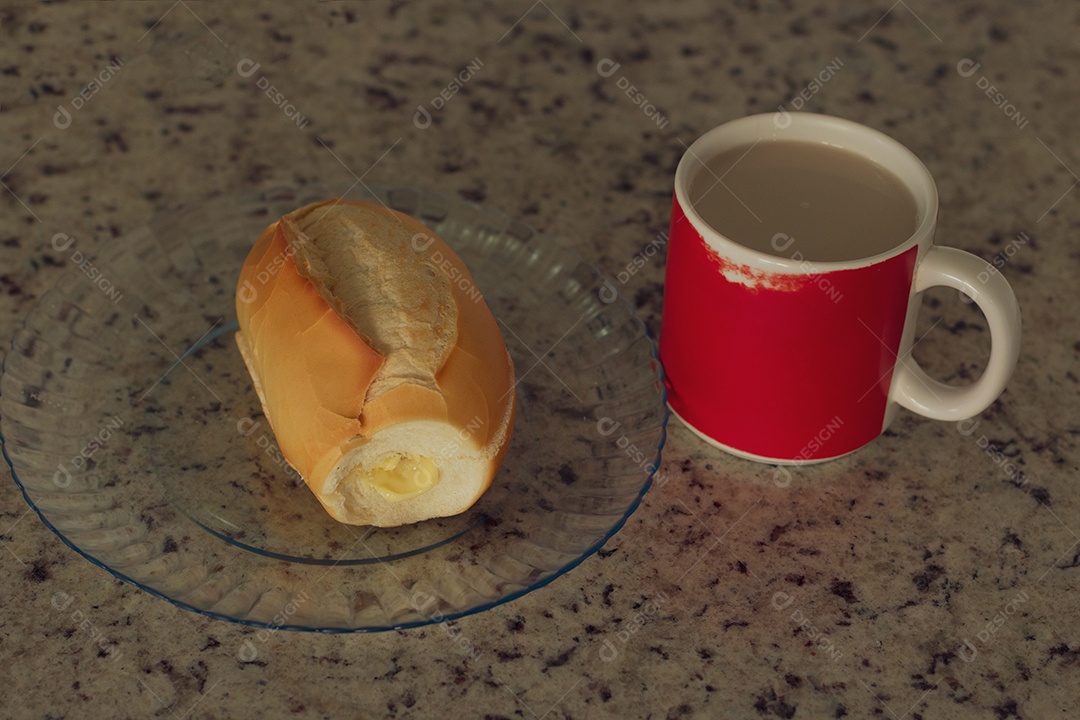 Xícara de café ao lado de pão francês sobre uma mesa