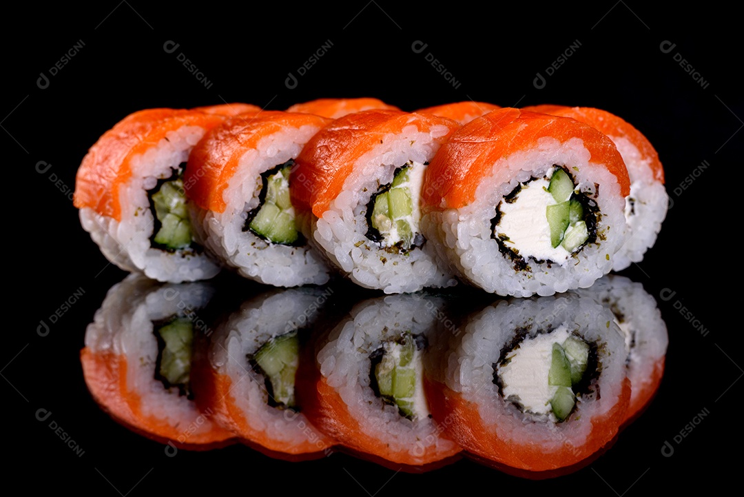 Rolos de sushi lindos e deliciosos frescos em um fundo preto. Elementos da culinária japonesa