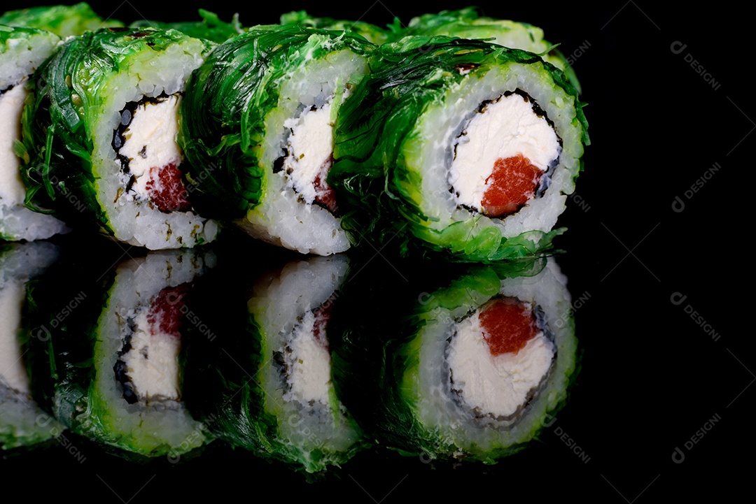 Rolos de sushi lindos e deliciosos frescos em um fundo preto. Elementos da culinária japonesa