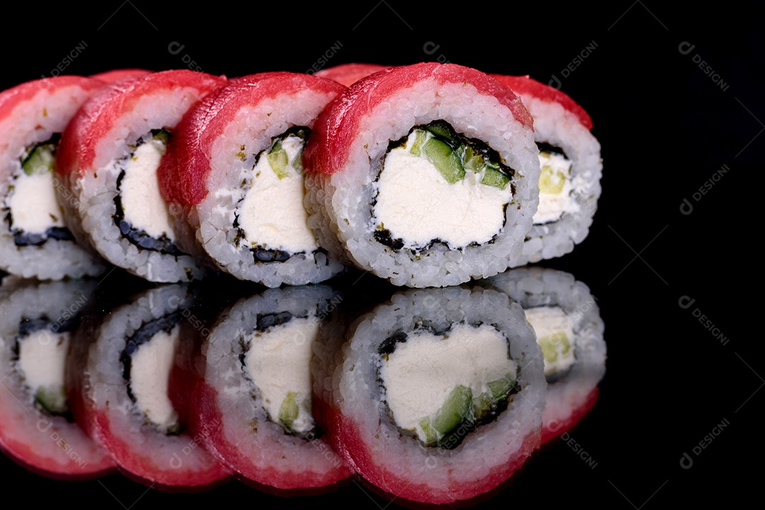 Rolos de sushi lindos e deliciosos frescos em um fundo preto. Elementos da culinária japonesa