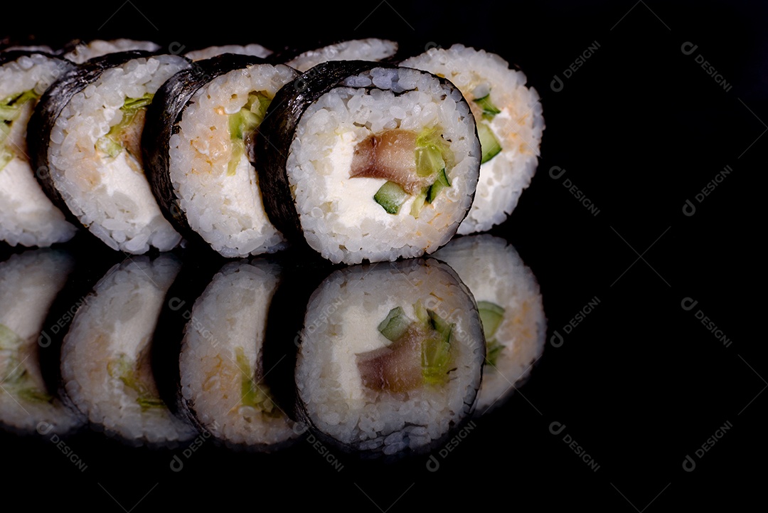 Rolos de sushi lindos e deliciosos frescos em um fundo preto. Elementos da culinária japonesa
