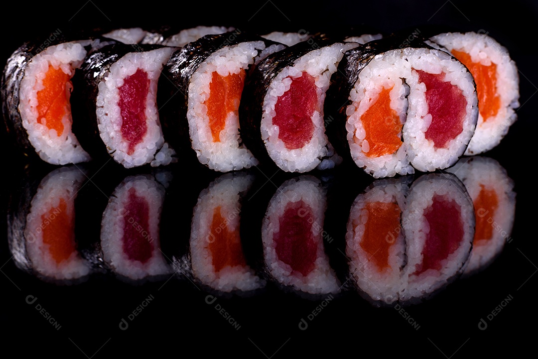 Rolos de sushi lindos e deliciosos frescos em um fundo preto. Elementos da culinária japonesa