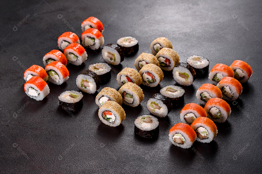 Rolos de sushi lindos e deliciosos frescos em um fundo preto. Elementos da culinária japonesa