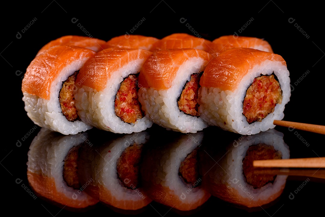 Rolos de sushi lindos e deliciosos frescos em um fundo preto. Elementos da culinária japonesa