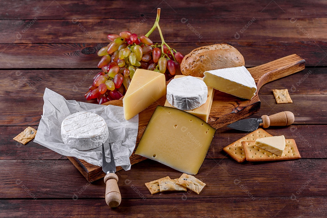 Lindo delicioso queijo camembert, parmesão, brie com uvas e figos em uma tábua de madeira.