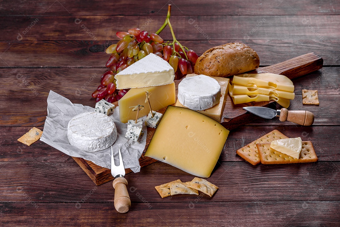 Lindo delicioso queijo camembert, parmesão, brie com uvas e figos em uma tábua de madeira.