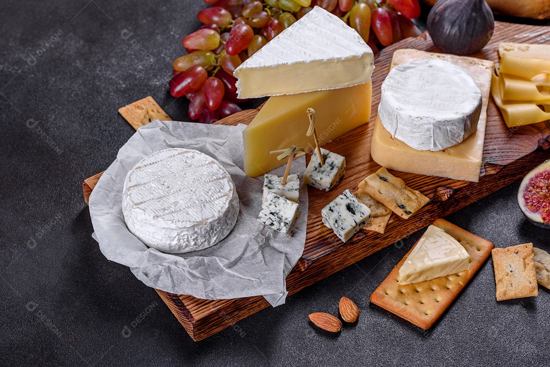 Lindo delicioso queijo camembert, parmesão, brie com uvas e figos em uma tábua de madeira.