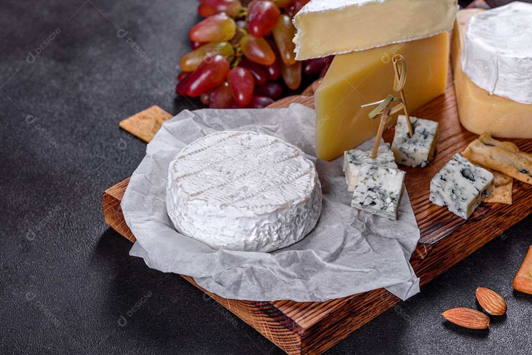 Lindo delicioso queijo camembert, parmesão, brie com uvas e figos em uma tábua de madeira.