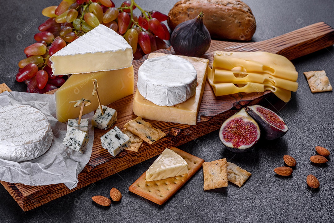Lindo delicioso queijo camembert, parmesão, brie com uvas e figos em uma tábua de madeira.