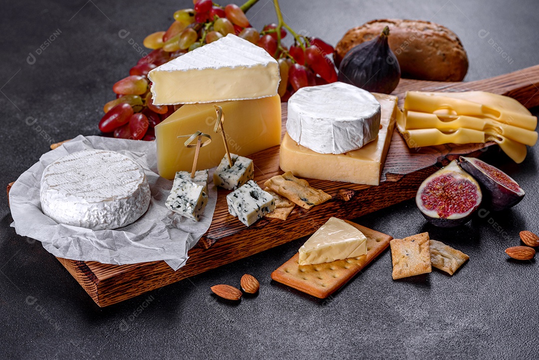 Lindo delicioso queijo camembert, parmesão, brie com uvas e figos em uma tábua de madeira.