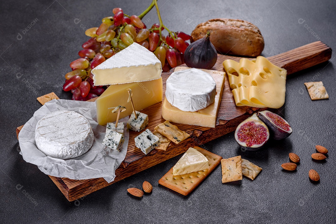 Lindo delicioso queijo camembert, parmesão, brie com uvas e figos em uma tábua de madeira.