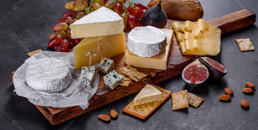 Lindo delicioso queijo camembert, parmesão, brie com uvas e figos em uma tábua de madeira.
