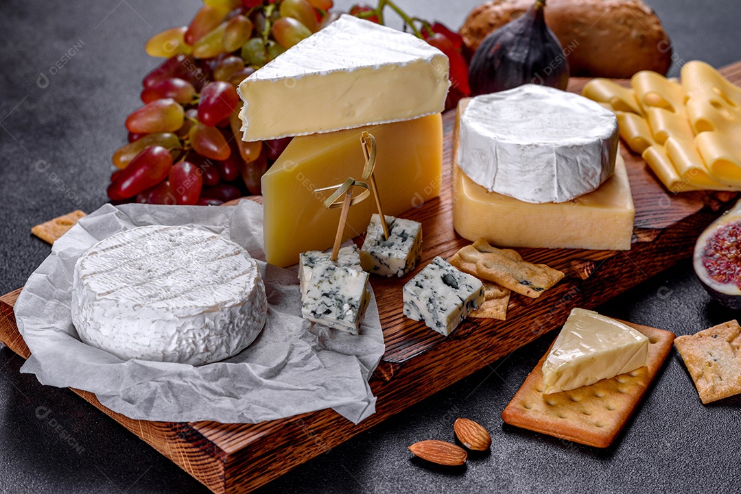 Lindo delicioso queijo camembert, parmesão, brie com uvas e figos em uma tábua de madeira.