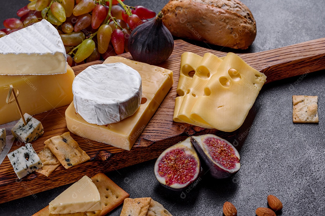 Lindo delicioso queijo camembert, parmesão, brie com uvas e figos em uma tábua de madeira.