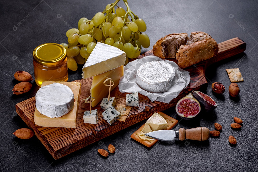 Lindo delicioso queijo camembert, parmesão, brie com uvas e figos em uma tábua de madeira.