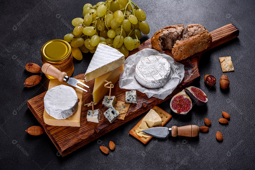 Lindo delicioso queijo camembert, parmesão, brie com uvas e figos em uma tábua de madeira.