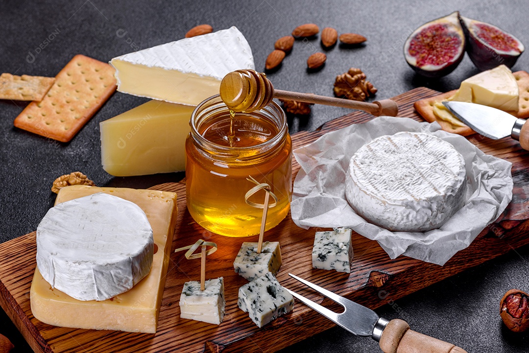 Lindo delicioso queijo camembert, parmesão, brie com uvas e figos em uma tábua de madeira.