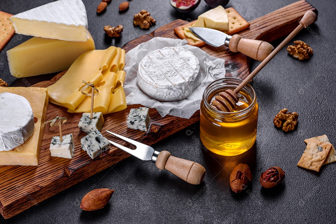 Lindo delicioso queijo camembert, parmesão, brie com uvas e figos em uma tábua de madeira.