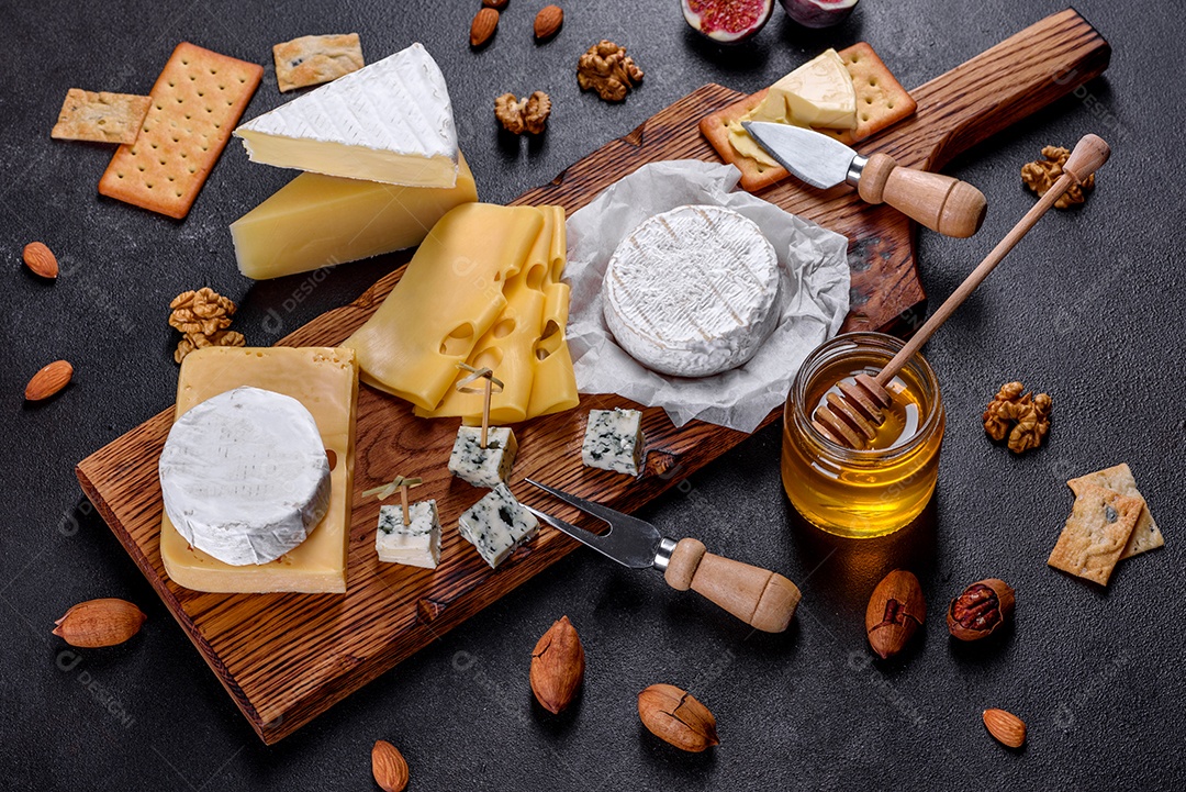 Lindo delicioso queijo camembert, parmesão, brie com uvas e figos em uma tábua de madeira.