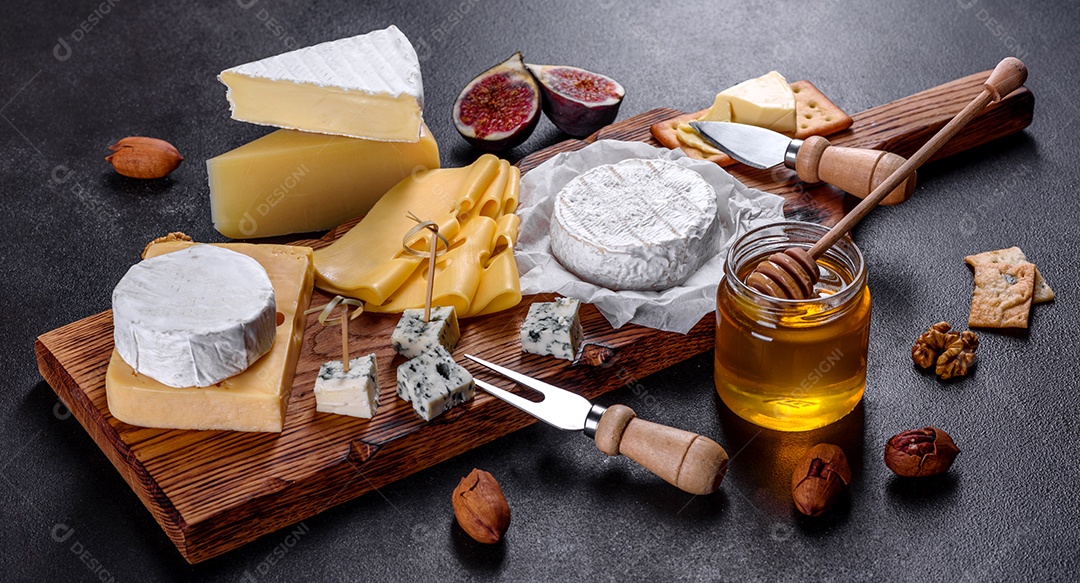 Lindo delicioso queijo camembert, parmesão, brie com uvas e figos em uma tábua de madeira.