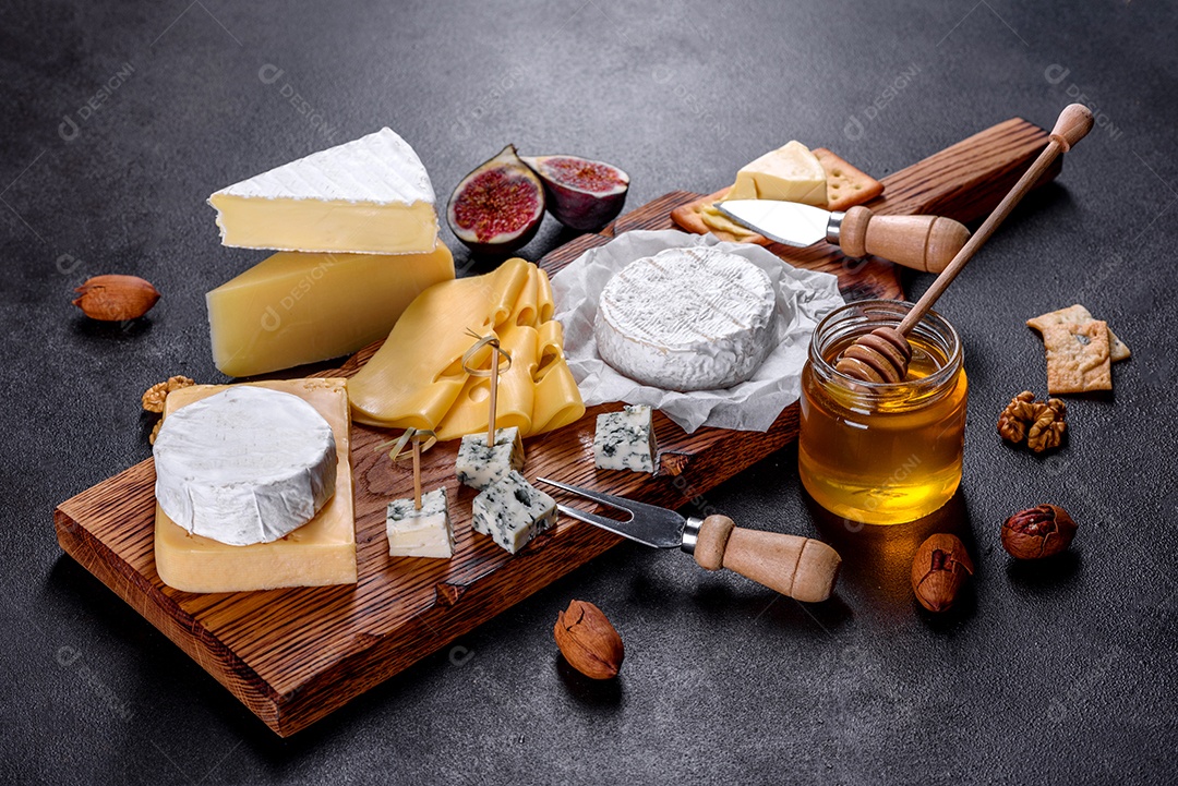 Lindo delicioso queijo camembert, parmesão, brie com uvas e figos em uma tábua de madeira.