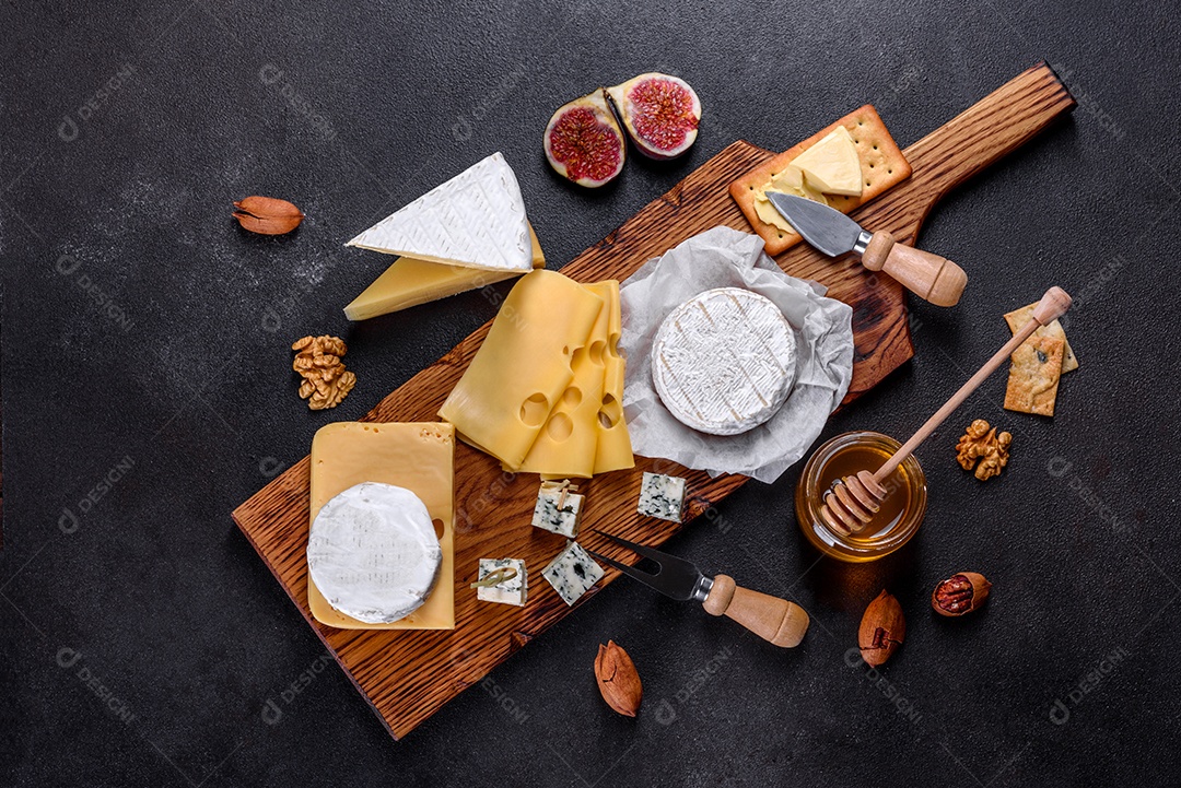 Lindo delicioso queijo camembert, parmesão, brie com uvas e figos em uma tábua de madeira.