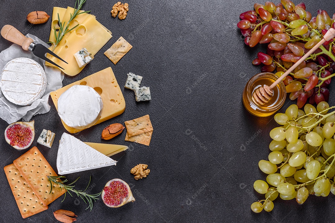 Lindo delicioso queijo camembert, parmesão, brie com uvas e figos em uma tábua de madeira.