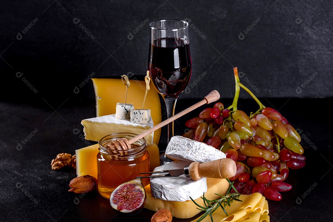 Lindo delicioso queijo camembert, parmesão, brie com uvas e figos em uma tábua de madeira.
