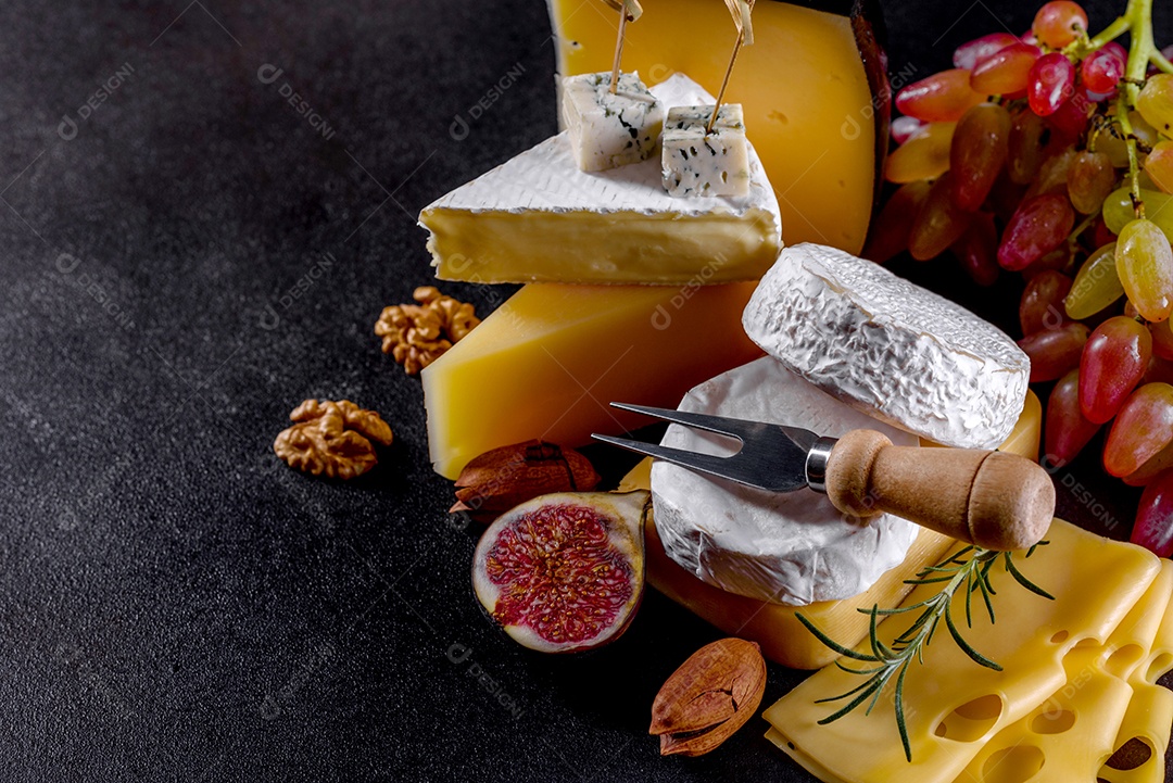 Lindo delicioso queijo camembert, parmesão, brie com uvas e figos em uma tábua de madeira.