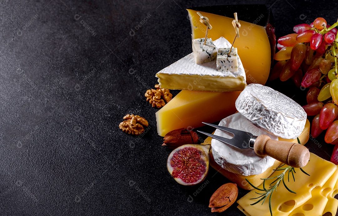 Lindo delicioso queijo camembert, parmesão, brie com uvas e figos em uma tábua de madeira.