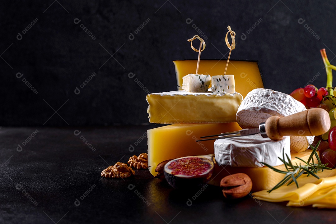 Lindo delicioso queijo camembert, parmesão, brie com uvas e figos em uma tábua de madeira.