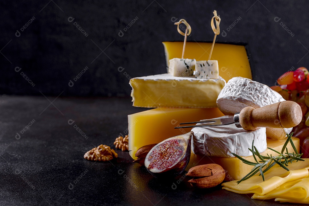 Lindo delicioso queijo camembert, parmesão, brie com uvas e figos em uma tábua de madeira.