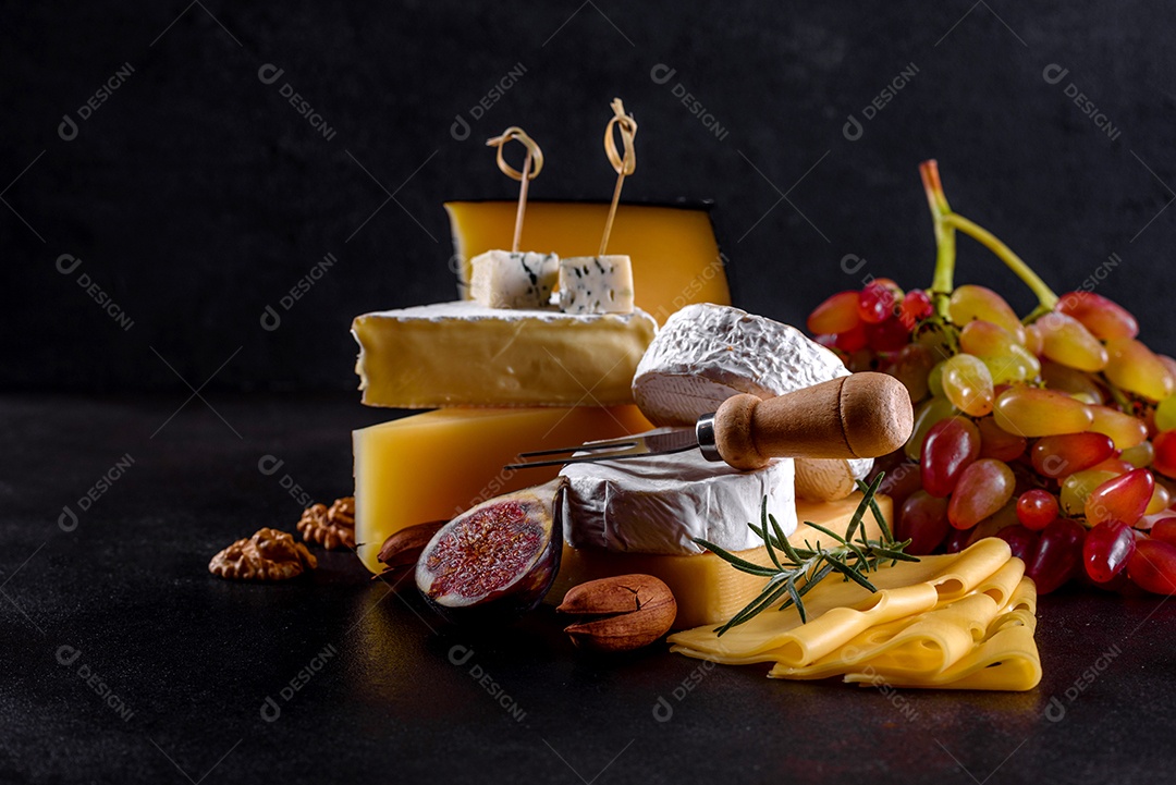 Lindo delicioso queijo camembert, parmesão, brie com uvas e figos em uma tábua de madeira.