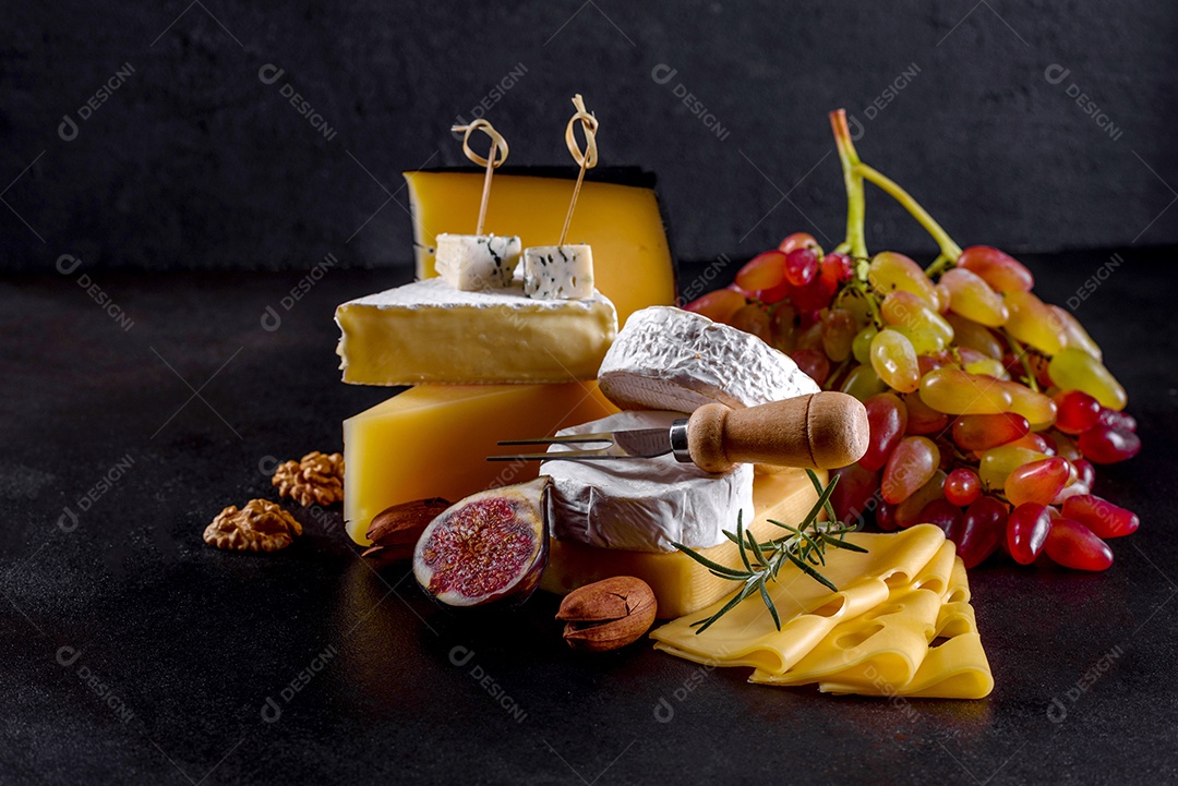 Lindo delicioso queijo camembert, parmesão, brie com uvas e figos em uma tábua de madeira.